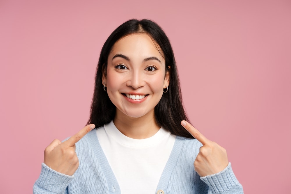Portrait,Of,Happy,Smiling,Asian,Woman,Pointing,At,Her,Perfect