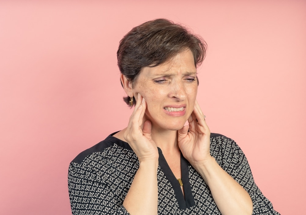 A TMJ patient holding her jaw