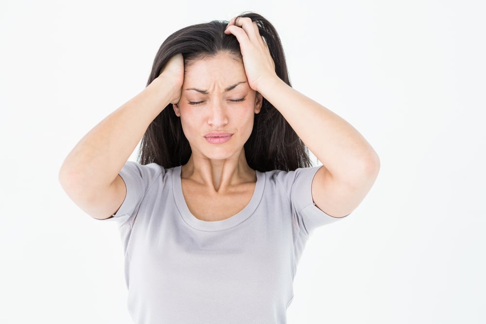 A woman with a TMJ headache holding her head