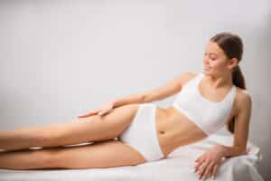 A woman lying on her side in white underwear after a waxing appointment