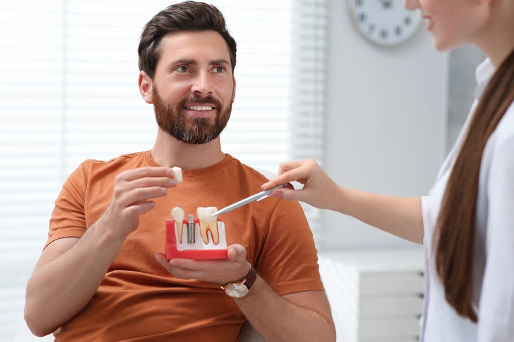 A dentist pointing to a model of the jaw explaining how dental crowns address severe damage