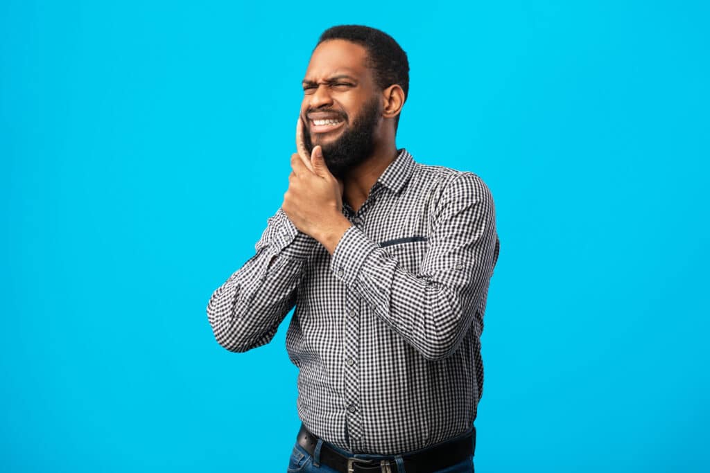 A man holding his cheek because he needs a root canal in Spokane