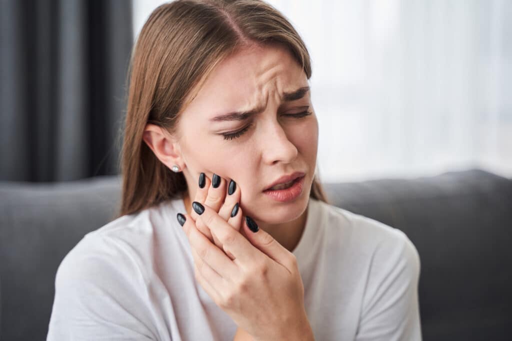 A woman with a toothache in Spokane holding her jaw