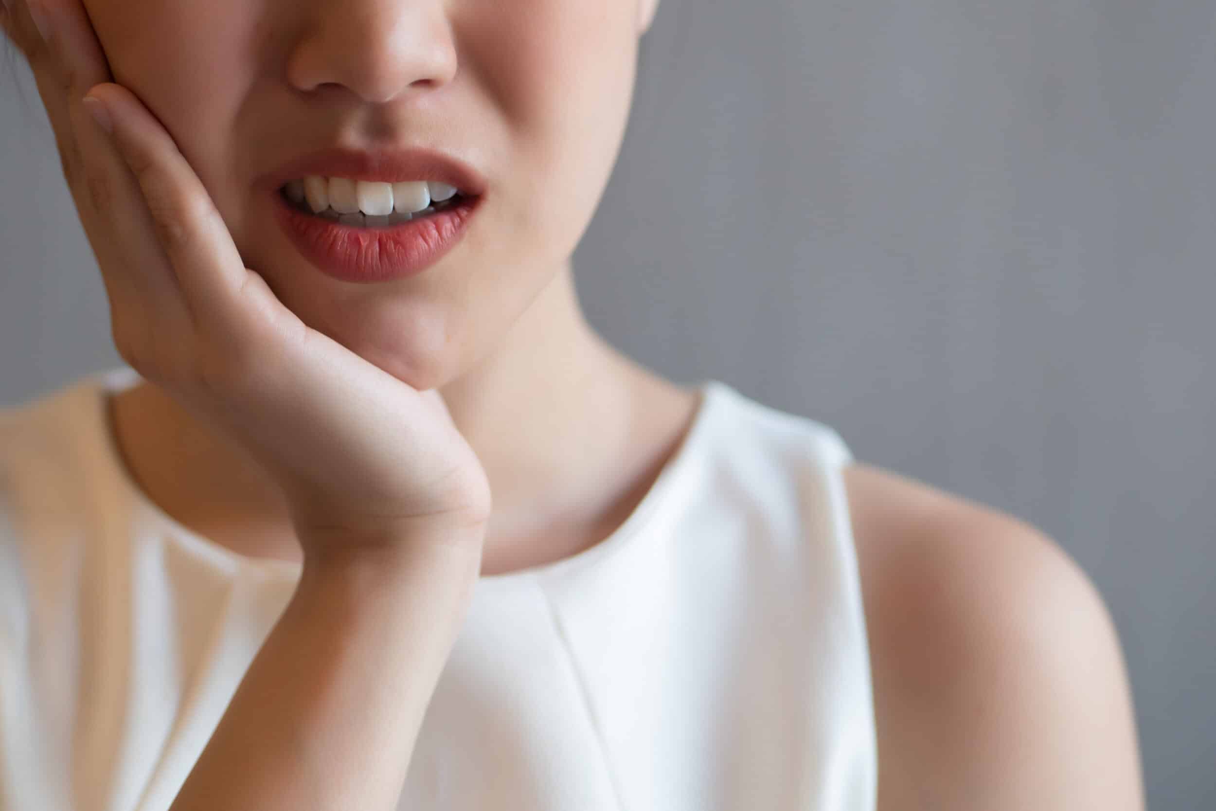 A close-up shot of a woman holding her jaw after a dental emergency