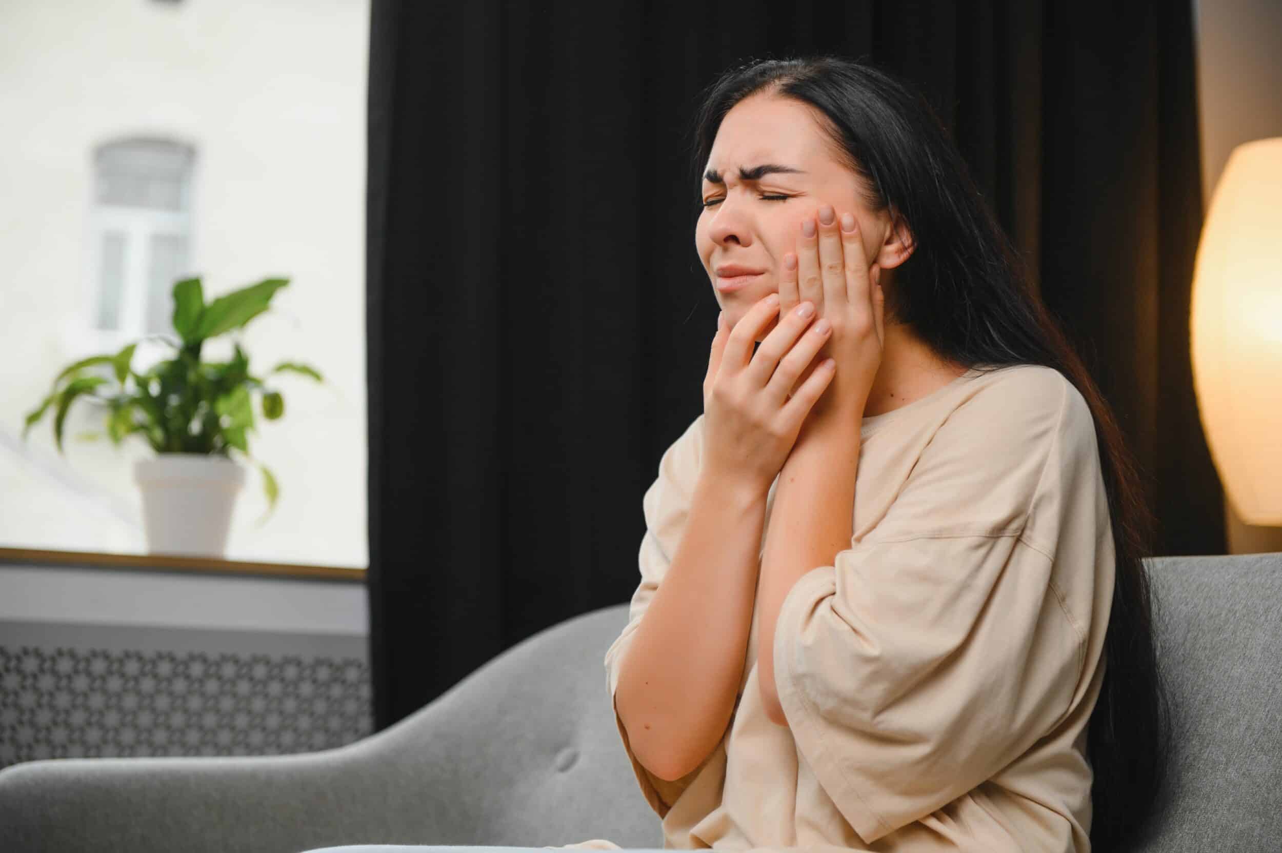 A woman with a dental emergency holding her jaw