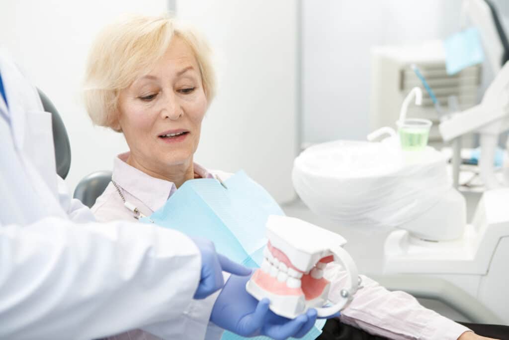 A woman sitting in a dentist’s chair looking a options for dentures in Spokane